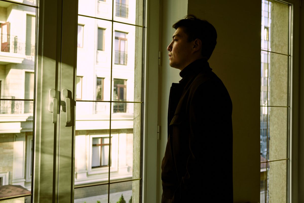 A person at their window, looking out over the neighborhood where they live
